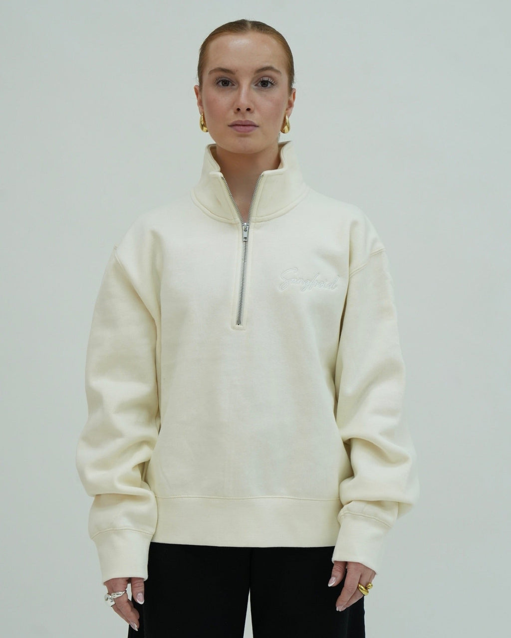 Person wearing a cream-colored half-zip sweatshirt against a plain background