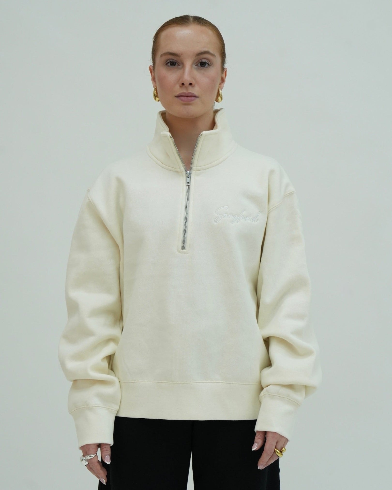 Person wearing a cream-colored half-zip sweatshirt against a plain background