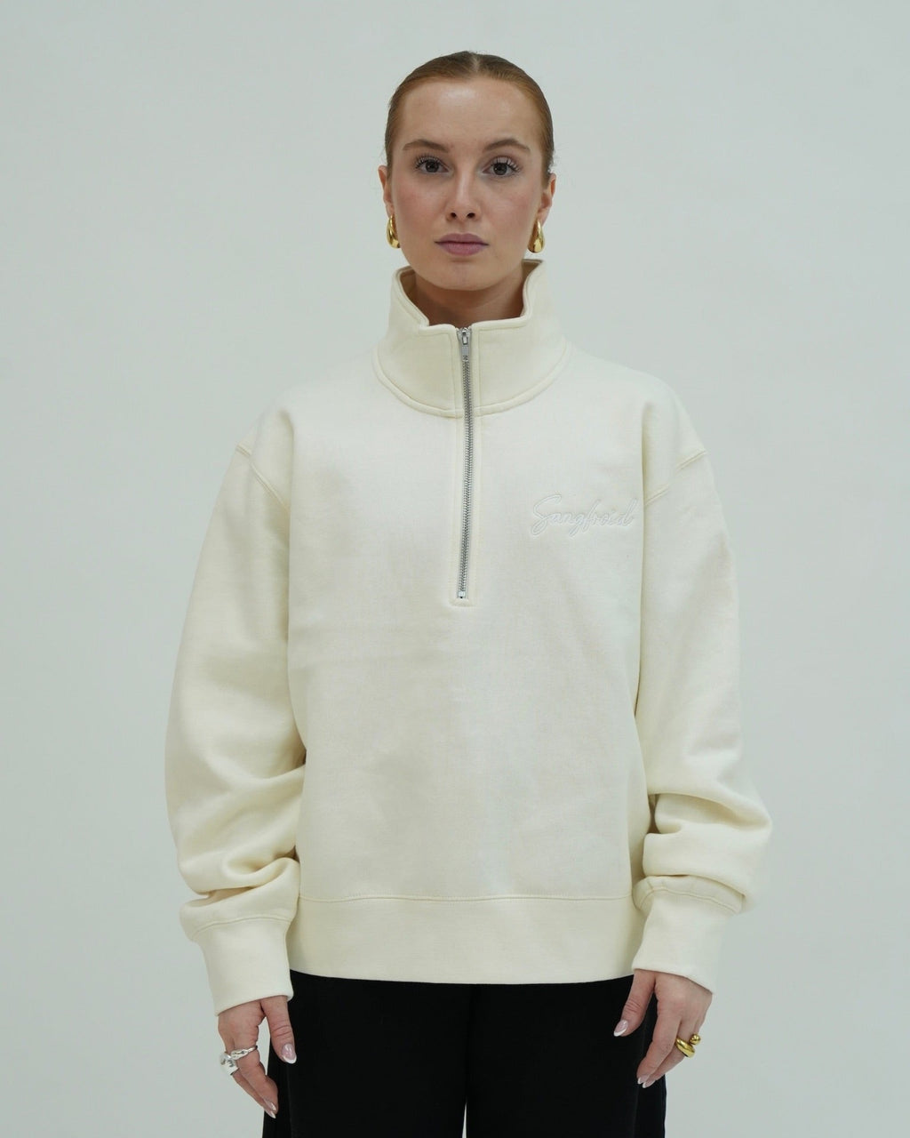Person wearing a cream-colored zip-up sweatshirt against a plain background