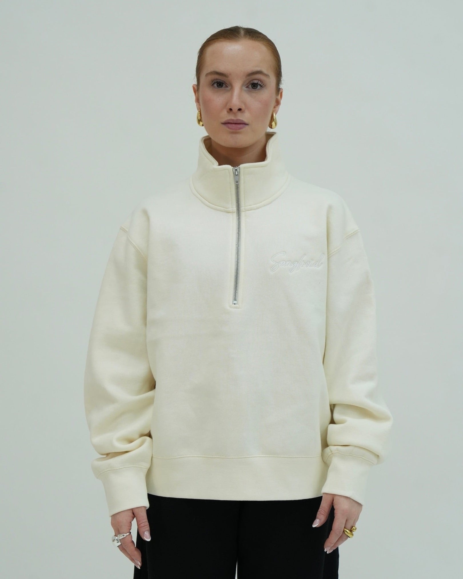 Person wearing a cream-colored zip-up sweatshirt against a plain background