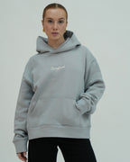 Person wearing a gray hoodie with 'Sangfroid' text on a plain background