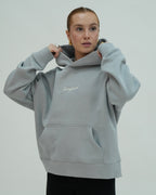 Person wearing a light gray hoodie with 'Sangfroid' branding on a plain background