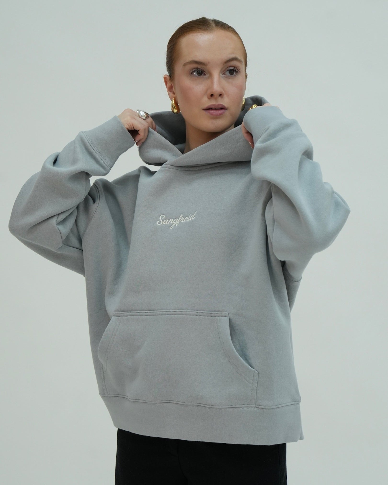 Person wearing a light gray hoodie with 'Sangfroid' branding on a plain background