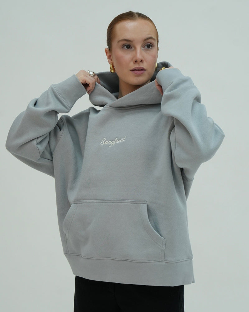 Person wearing a light gray hoodie with 'Sangfroid' branding on a plain background
