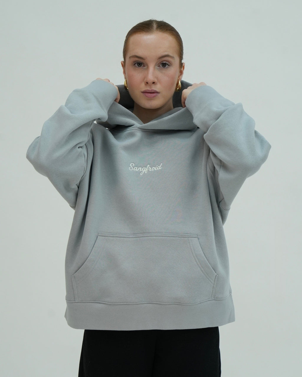 Person wearing a light gray hoodie with 'Sangfroid' branding on a plain background