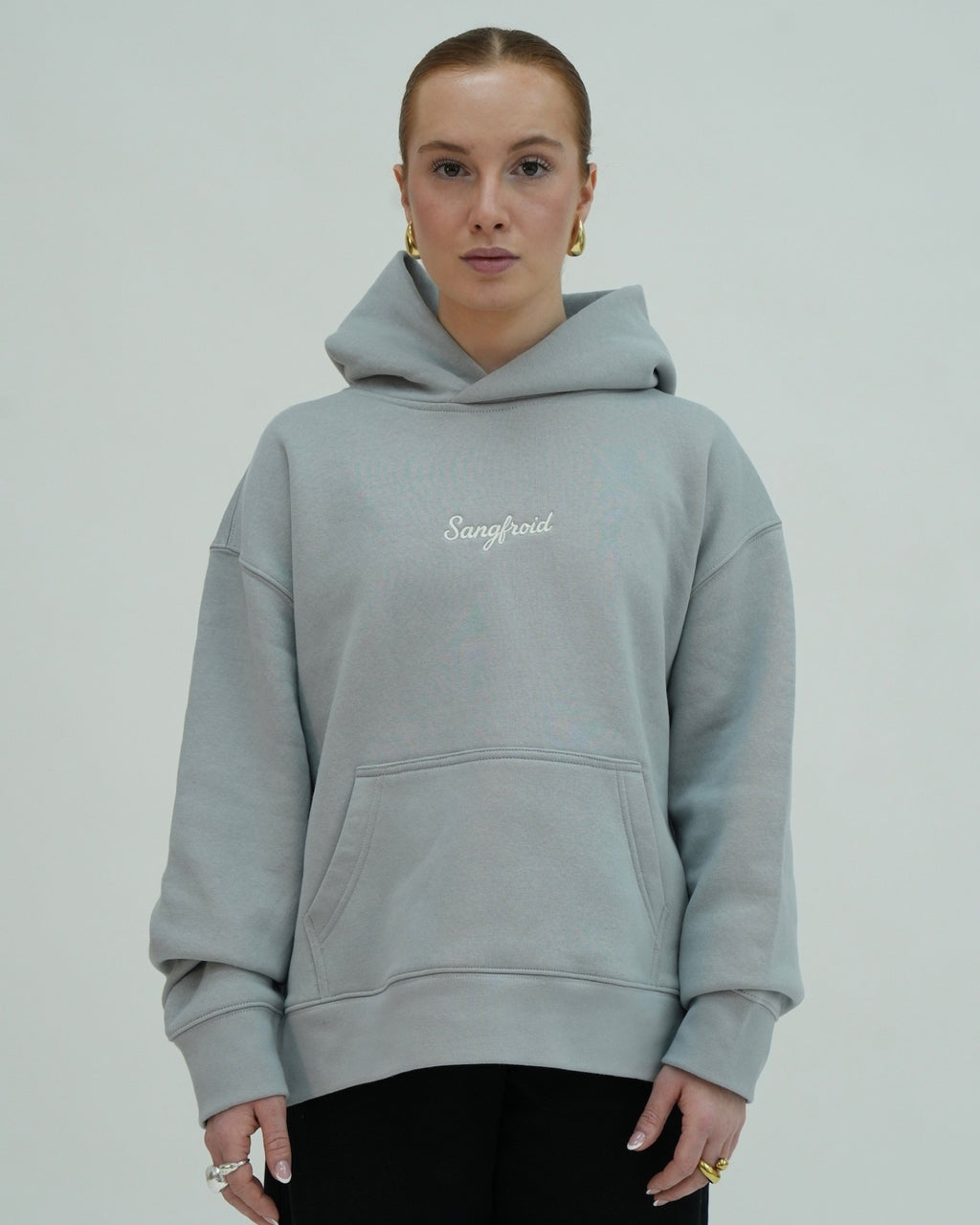 Person wearing a light gray hoodie with 'Sangfroid' branding on a plain background