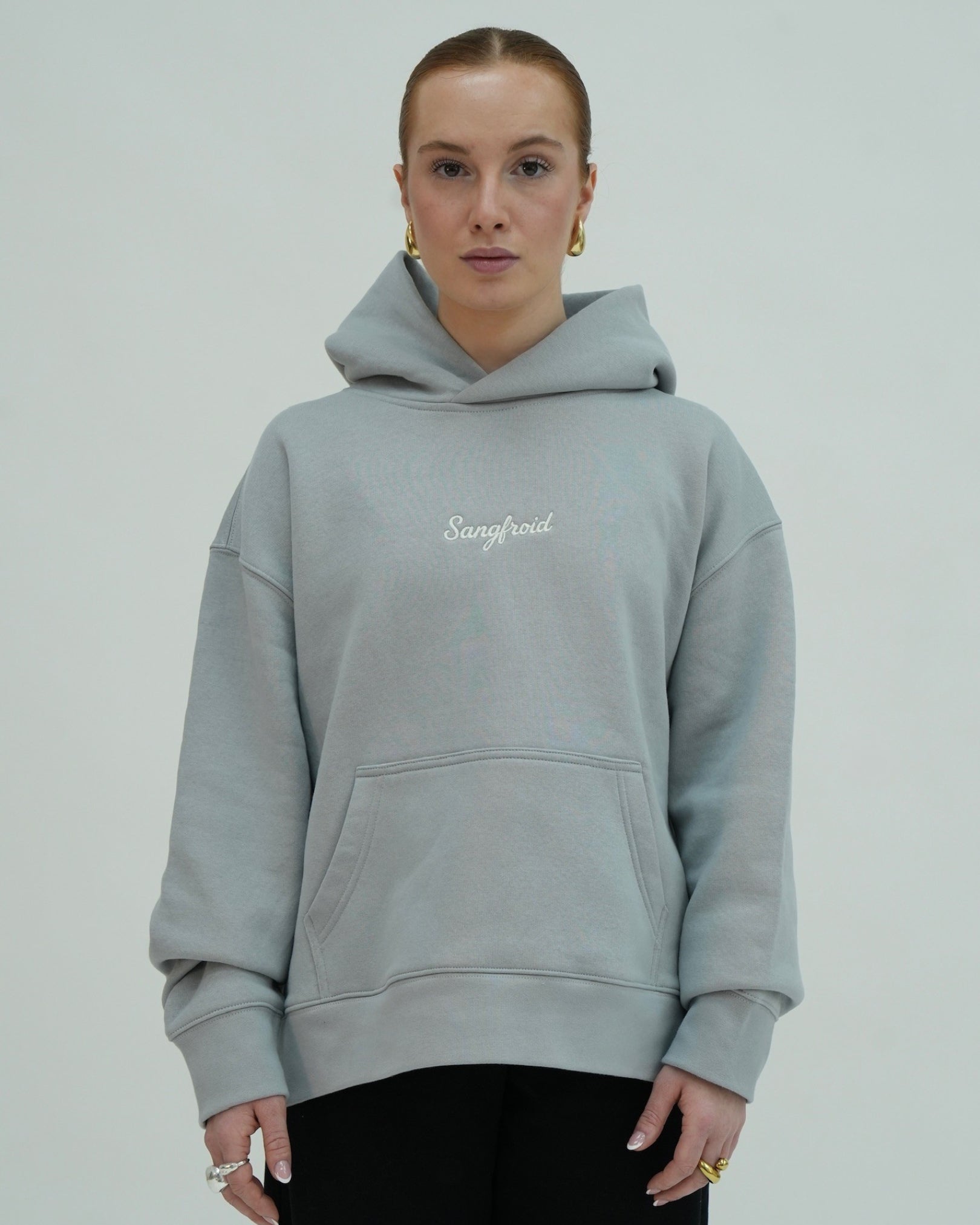 Person wearing a light gray hoodie with 'Sangfroid' branding on a plain background
