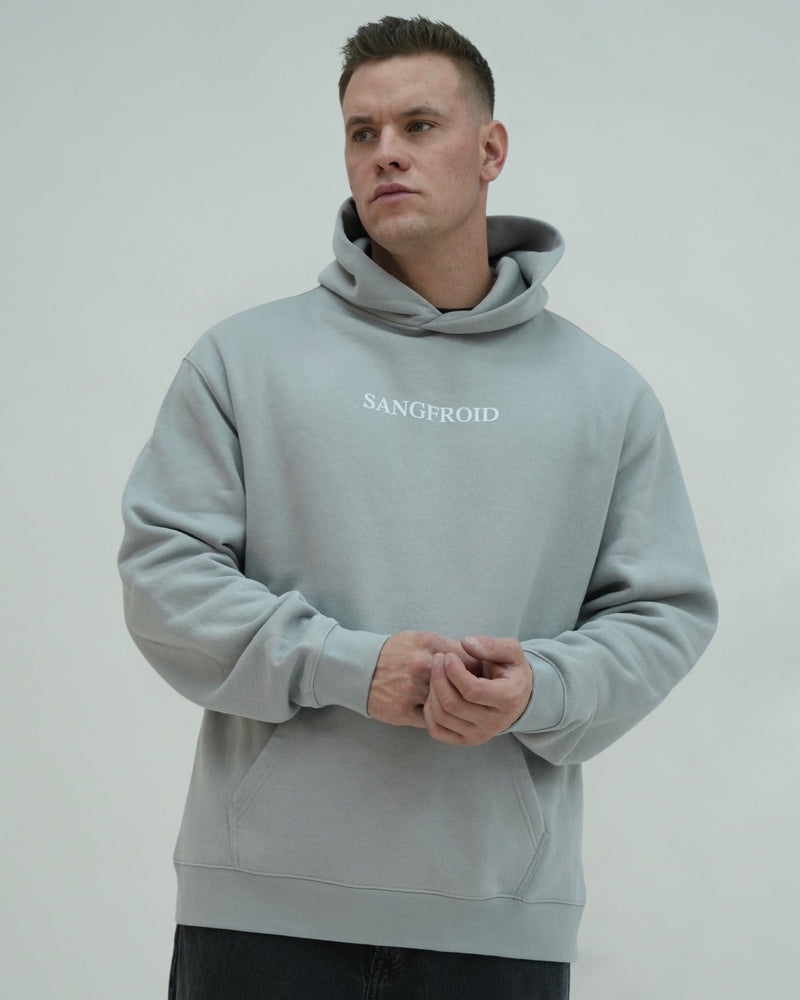 Man wearing a light gray hoodie with 'SANGFROID' text on a plain background