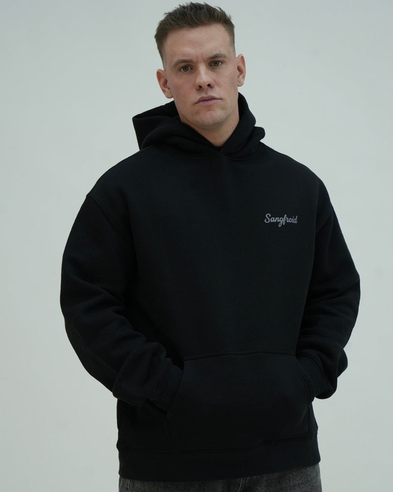 Man wearing a black hoodie with a brand logo on a gray background