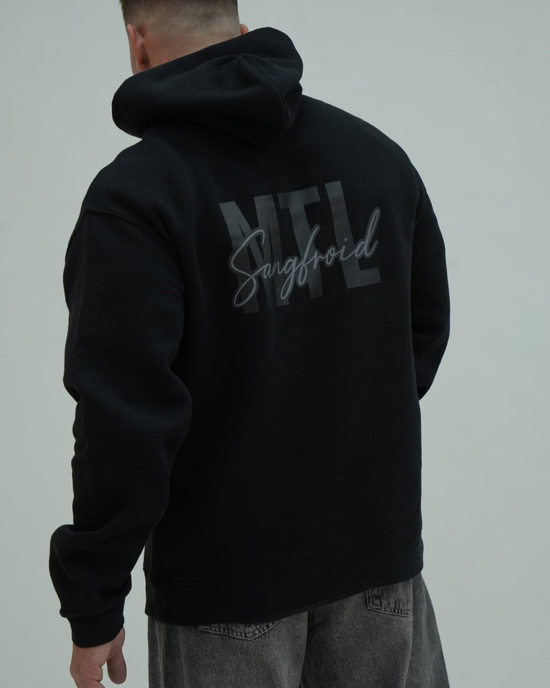 Person wearing a black hoodie with 'MTL Sangfroid' text on the back against a gray background