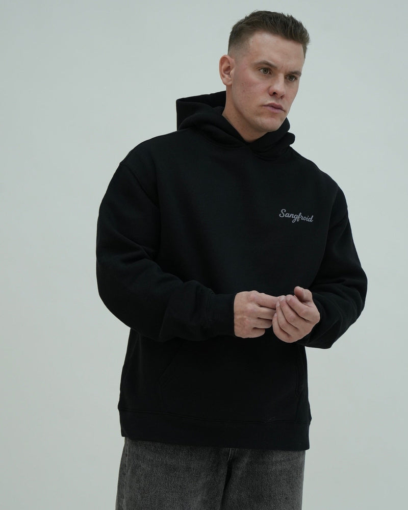 Man wearing a black hoodie with 'Sangfroid' logo on a gray background