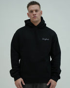 Man wearing a black hoodie with 'Sangfroid' branding on a plain background