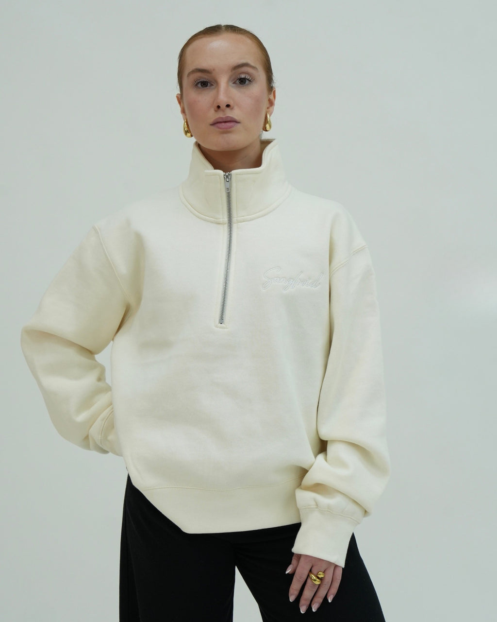 Person wearing a cream-colored half-zip sweatshirt against a plain background