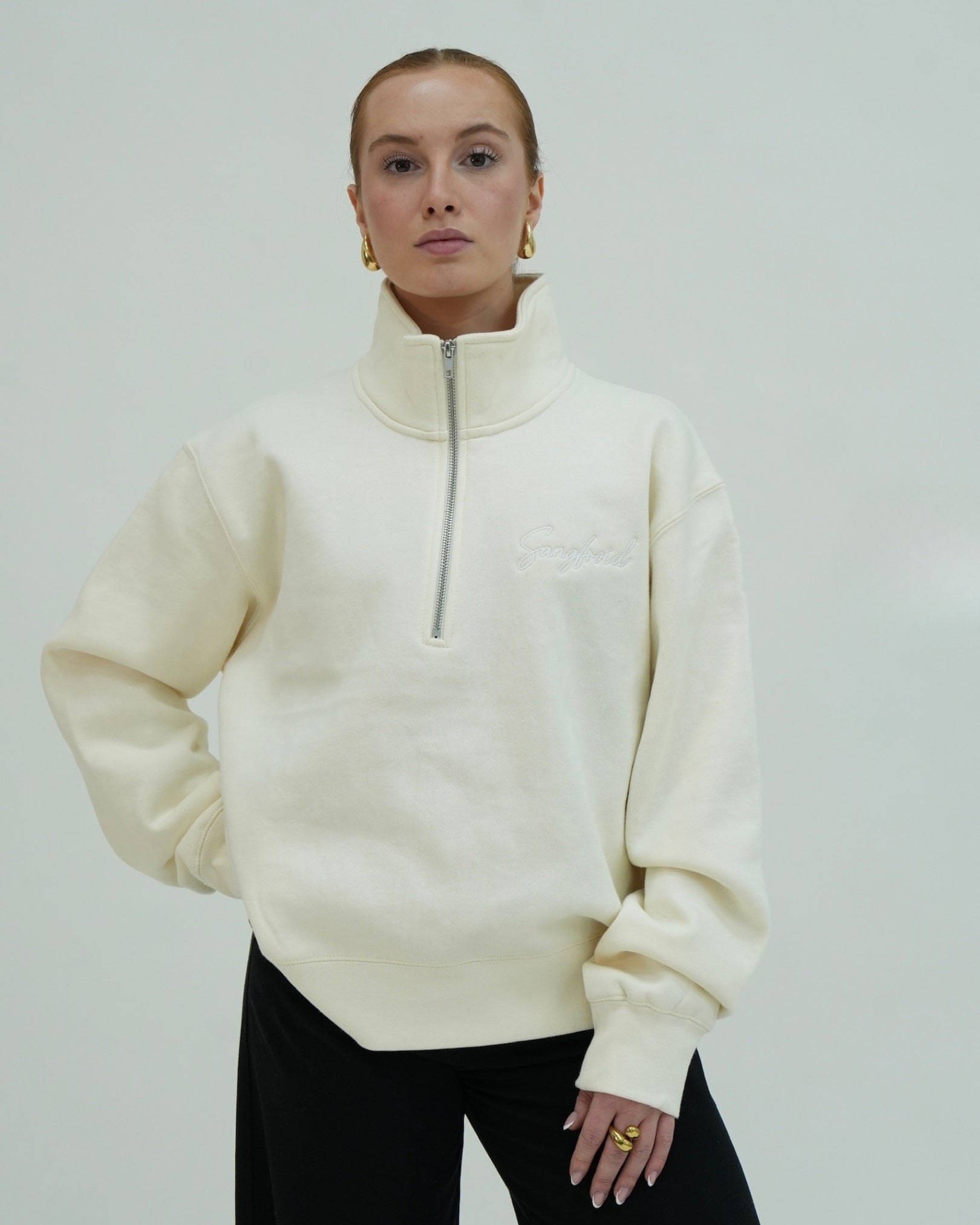 Person wearing a cream-colored half-zip sweatshirt against a plain background
