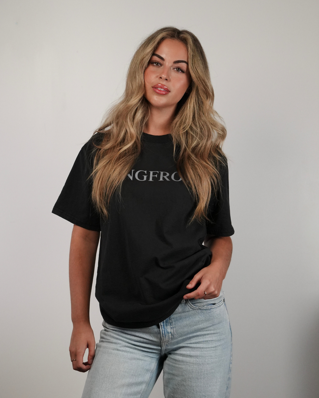 Woman wearing a black t-shirt with 'SANGFROID' logo against a plain background