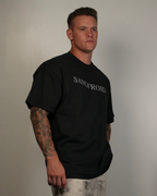 Man wearing a black t-shirt with 'SANGFROID' text against a plain background