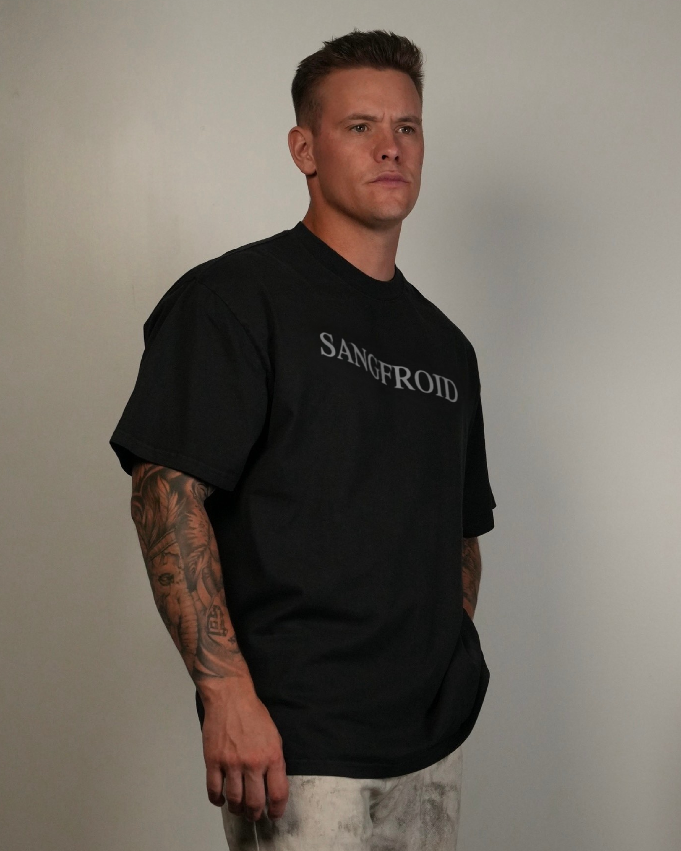 Man wearing a black t-shirt with 'SANGFROID' text against a plain background
