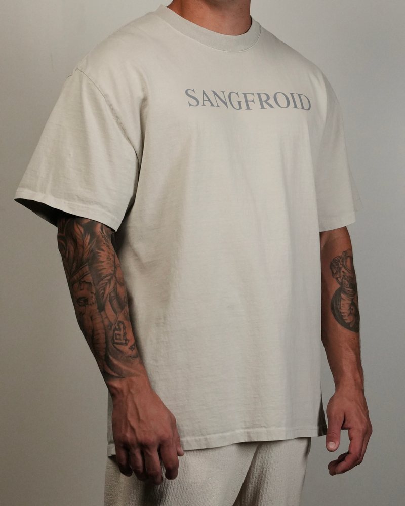 Person wearing a beige t-shirt with 'SANGFROID' text, standing against a plain background.