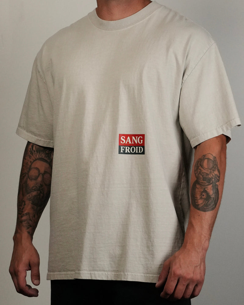 Person wearing a beige t-shirt with a logo on a plain background