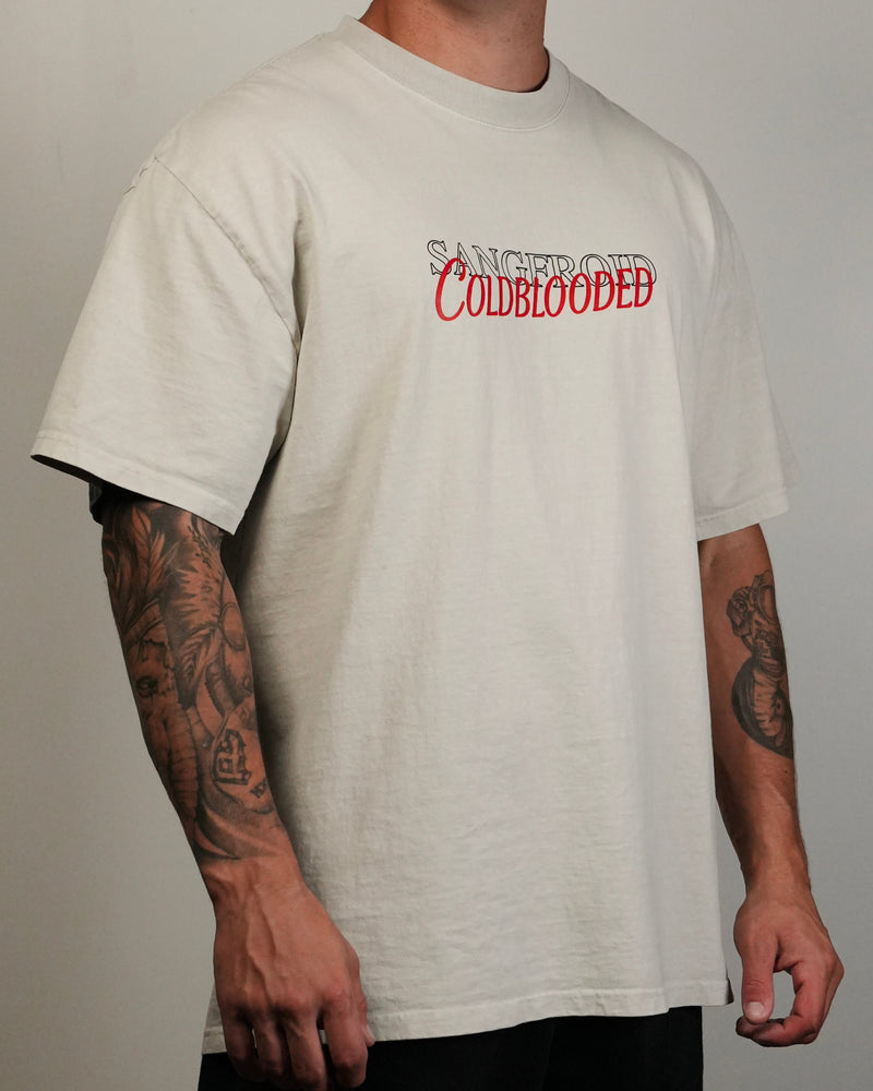 Person wearing a beige t-shirt with 'SANGFROID Coldblooded' text in red on a plain background