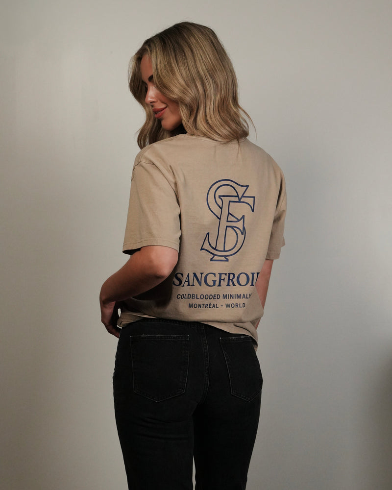 Person wearing a beige t-shirt with a logo and text on the back against a plain background