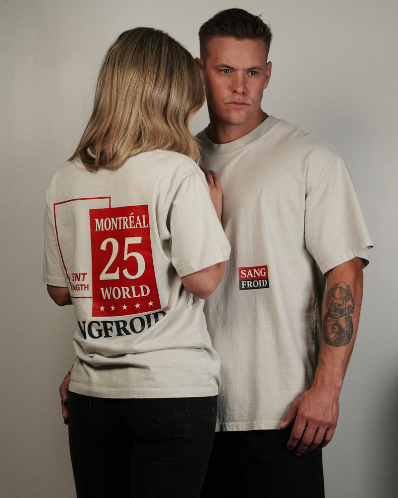 Two people wearing matching t-shirts with text and numbers on a plain background
