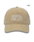 A beige washed cotton baseball cap with white embroidered text reading 'SANG FROID' on the front, shown against a plain white background with a small 'NEW' badge in the top right corner.